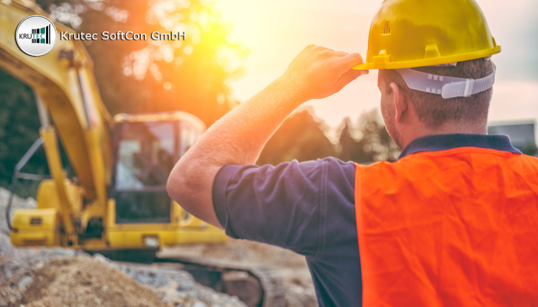 Bauarbeiter mit einem gelben Sicherheitshelm vor einer Baustelle mit Bagger